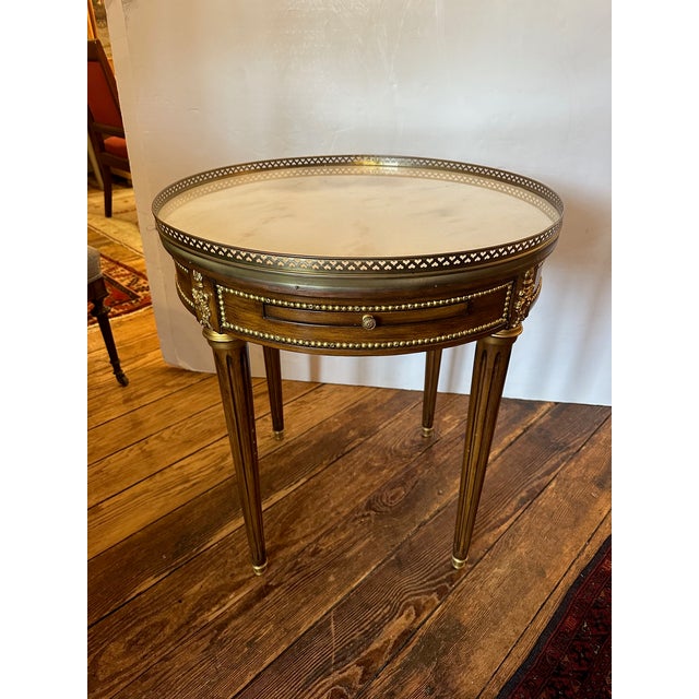 Very pretty round medium sized end table having white marble top with pierced brass gallery. The polished mahogany has...