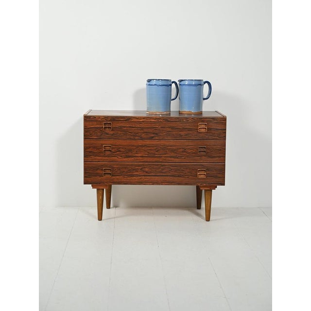 1950s–1960s chest of drawers with three drawers, recessed double-loop handles, and turned legs. Laminate with a rosewood-...