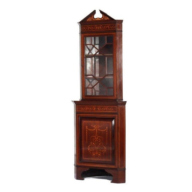 An antique corner cabinet crafted around 1900, showcasing the aesthetic of the Classical Revival period. This diminutive...