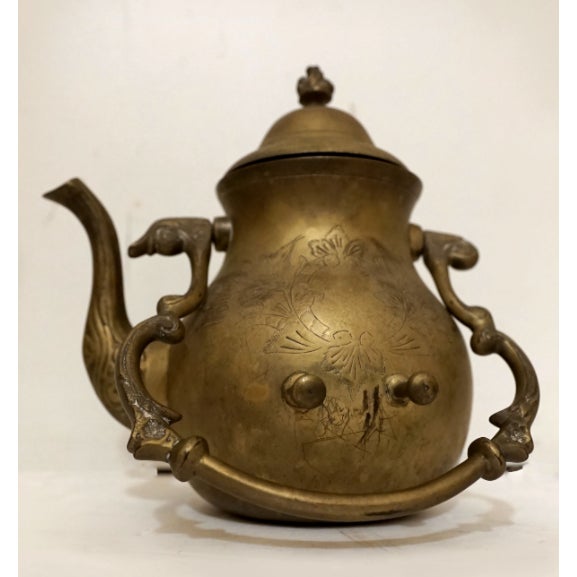 An engraved brass teapot or hot water kettle has the most beautiful patina. The handle has scroll work on this 19th...
