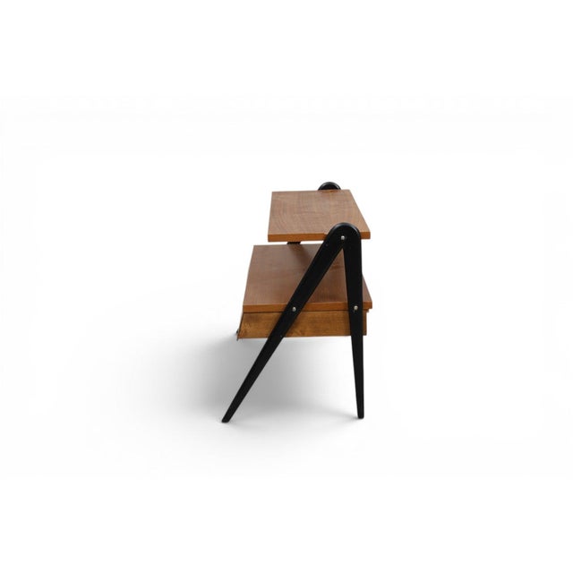 This 1960s Swedish teak shelf pairs warm wood surfaces with striking black uprights, a graphic contrast that gives the...