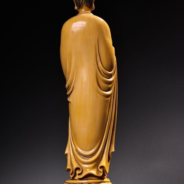 This elegant sculpture depicts a standing Buddha in a classic pose, crafted with a fine ivory-tone finish that resembles...