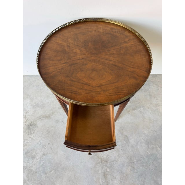 Refined vintage Baker Furniture Louis XVI-style bouillotte table, exquisitely crafted in walnut with elegant neoclassical...