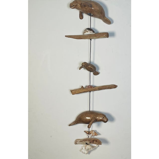 Cute Florida coastal mobile sculpture with ceramic manatee figures, sea shells and driftwood pieces.