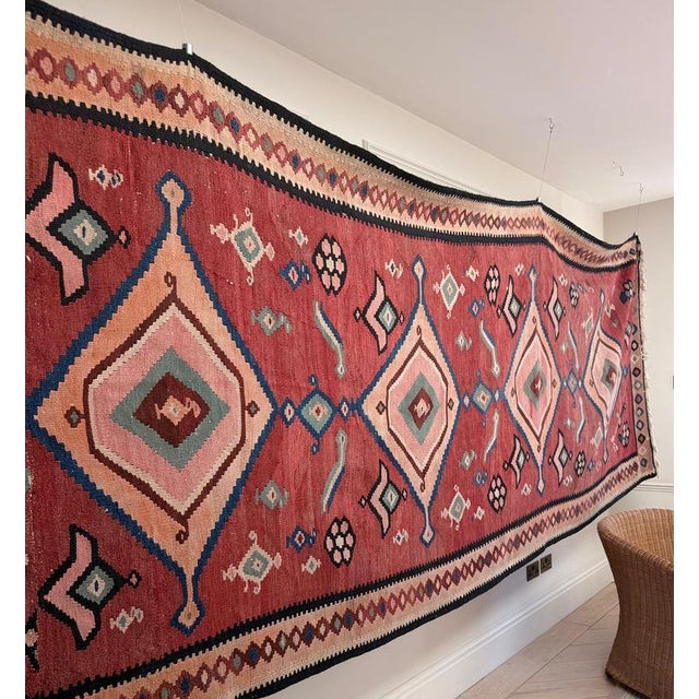 An exceptional large-scale vintage kilim, handwoven in wool and extending to almost five metres in length. The warm...