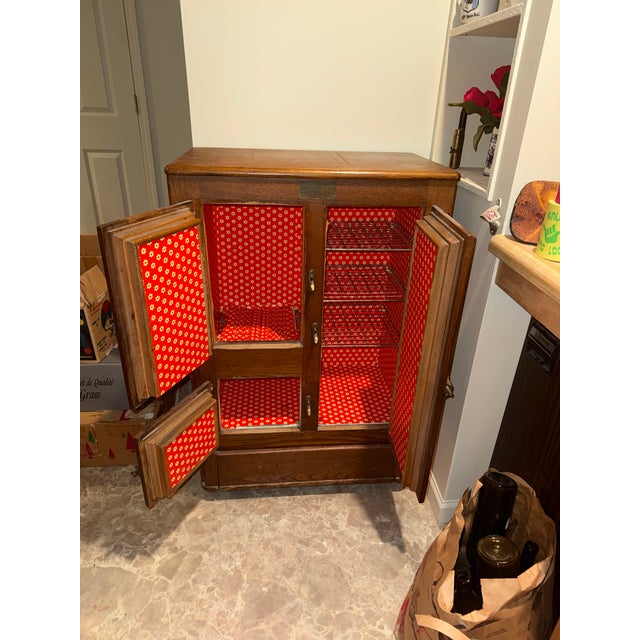 A wooden cabinet featuring three hinged doors and nickel-plated brass hardware, showcasing prominent wood grain and a...