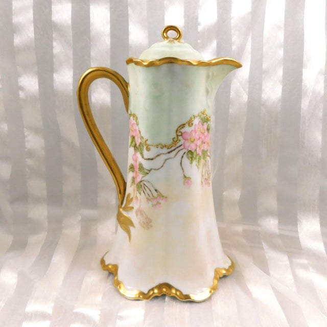 This is a pale green Haviland chocolate pot with a backstamp that is dated 1876 to 1889. The chocolate pot has a pink...