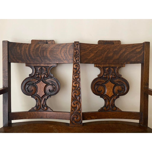 Antique solid oak two-seat settle with carved back splats and original dark finish. Manufactured in Grand Rapids,...