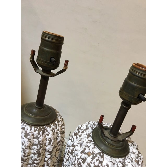 A pair of mid century modern Pottery lamps. Features brown and white lemon peel glaze. Assembled differently to accentuate...