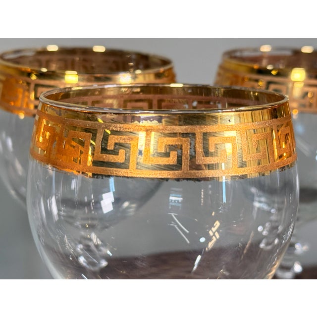This set of six clear crystal wine goblets features wide bowls, slender stems, and gold Greek key bands at the rims, with...