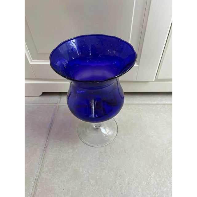 Beautiful blue - cobalt blue glass with clear pedestal base . Scalloped edge on top rim. Use for candles, flowers or any...