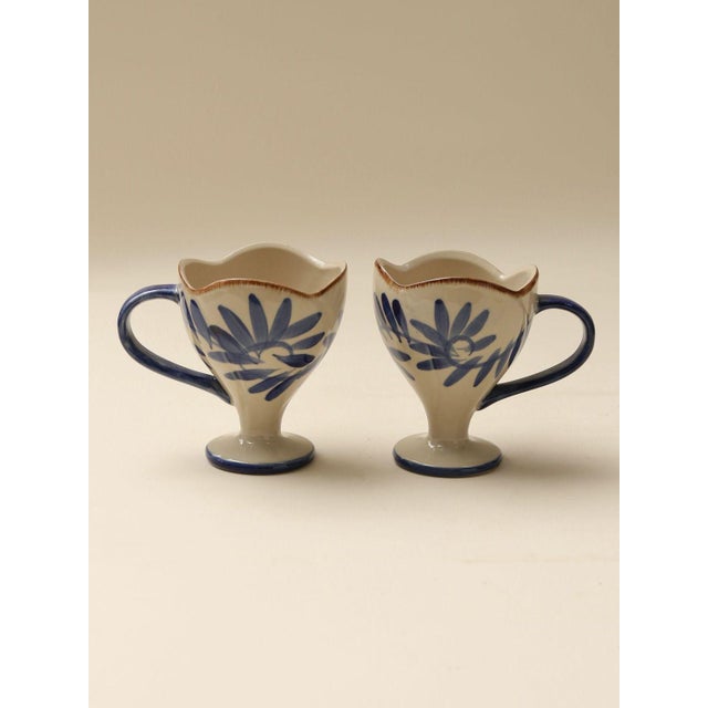 A set of vintage ceramic cups featuring petal-shaped rims and hand-painted blue floral patterns. With their unique design,...
