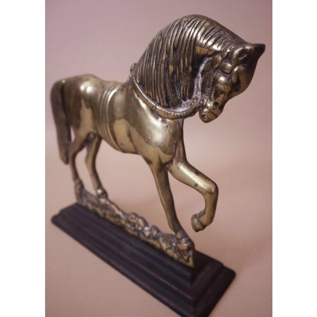 Heavy vintage solid brass horse pointing front leg, mounted on metal stand.