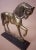 Heavy vintage solid brass horse pointing front leg, mounted on metal stand.