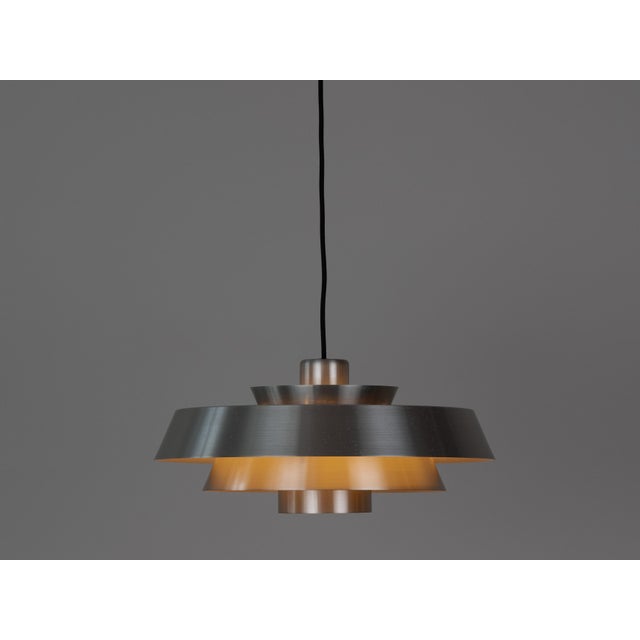 The aluminum Nova lamp, designed by Jo Hammerborg in 1963. When lit, the lamp provides a soft, glare-free downward glow,...