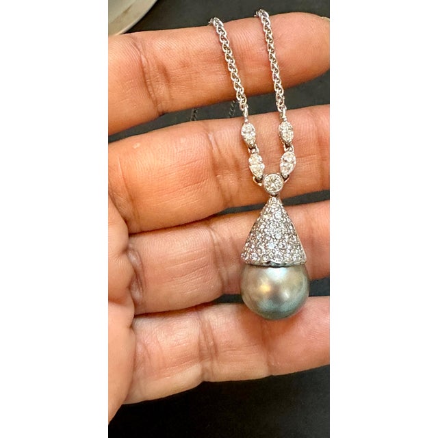Introducing the exquisite 14 mm Black Tahitian Pearl & Diamond Pendant in 18K Gold, accompanied by a 14K Gold Chain. This...