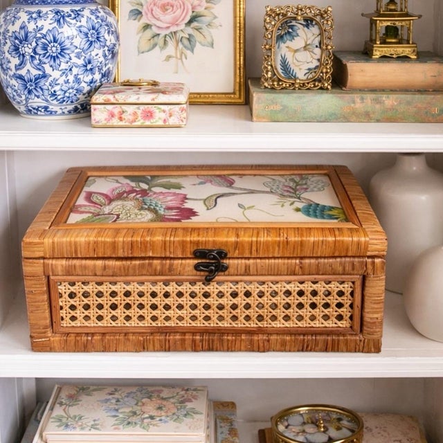 Vintage rattan and cane storage box featuring a hinged glass top and a custom designer fabric insert. The woven...