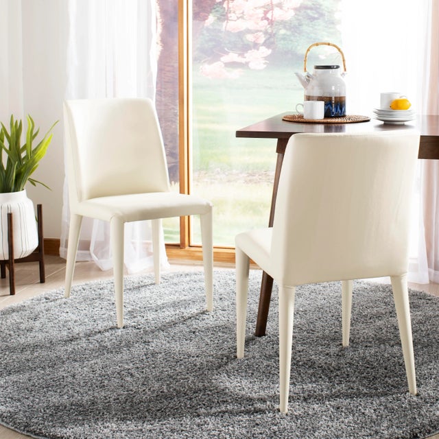 Modern elegance defines the clean-cut lines of this set of two side chairs covered in easy-care buttercream PU...
