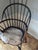 This appears to be a traditional comb-back Windsor armchair featuring a historic distressed black-painted finish and a...