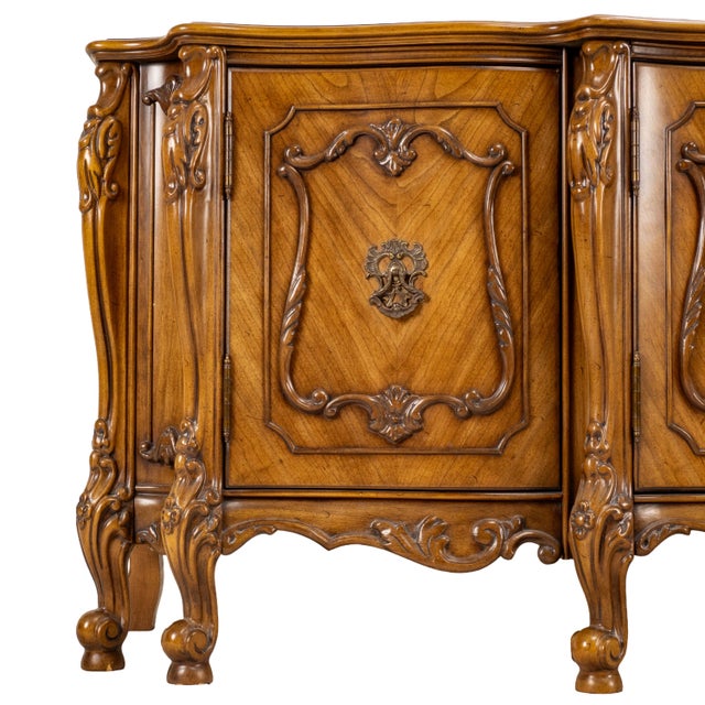 An elegant vintage French Provincial credenza showcasing exceptional craftsmanship and timeless design. Rich walnut...