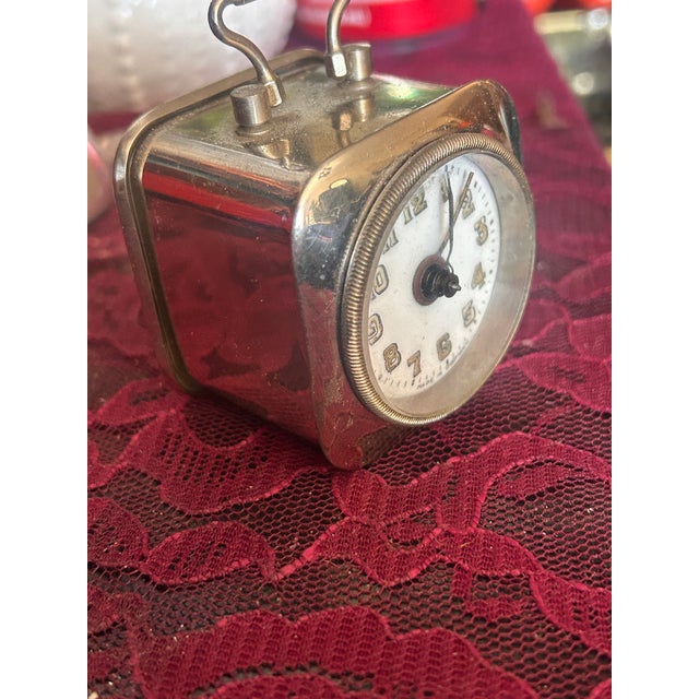 Petite vintage mechanical German travel alarm clock in a silver-tone folding case, featuring a classic dial with raised...