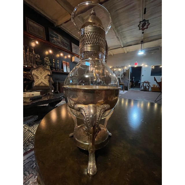 Elegant vintage glass coffee carafe featuring ornate silver-tone metal detailing, a beautifully sculpted scrolling handle,...