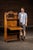 Solid oak drop-front secretary featuring a carved foliate crest, turned spindle supports, and open shelving beneath the...