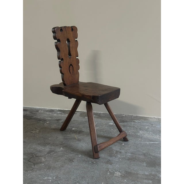 A sculptural chair crafted from wood with a dark finish, Italian craftsmanship from the 1950s. The chair features a flat,...