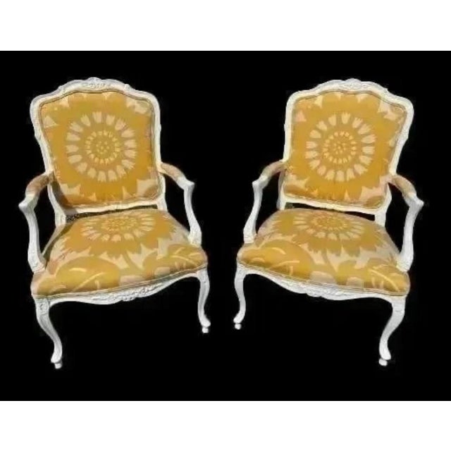 This stunning pair of vintage bergere chairs painted glossy white with custom yellow and white floral linen upholstery are...