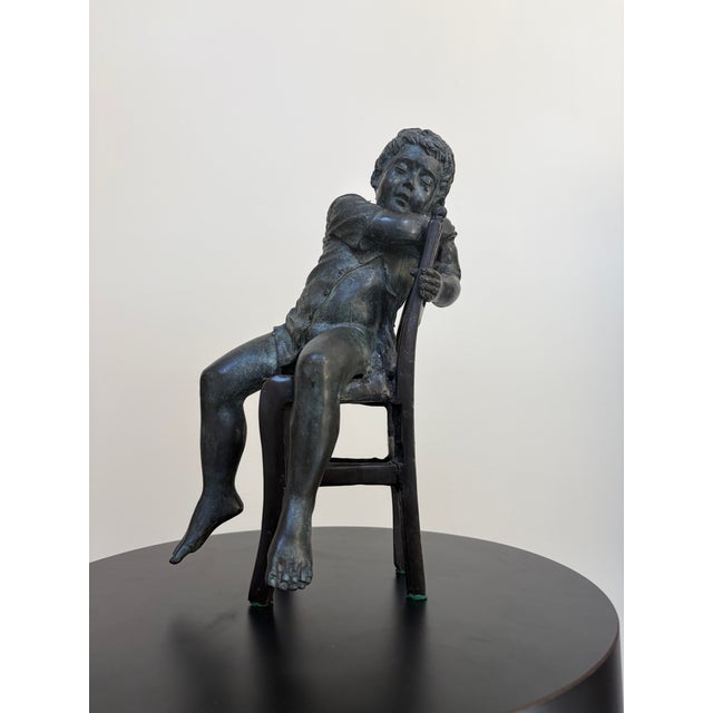 Vintage bronze figural sculpture depicting a young boy asleep in a chair, finished with an intentionally applied verdigris...