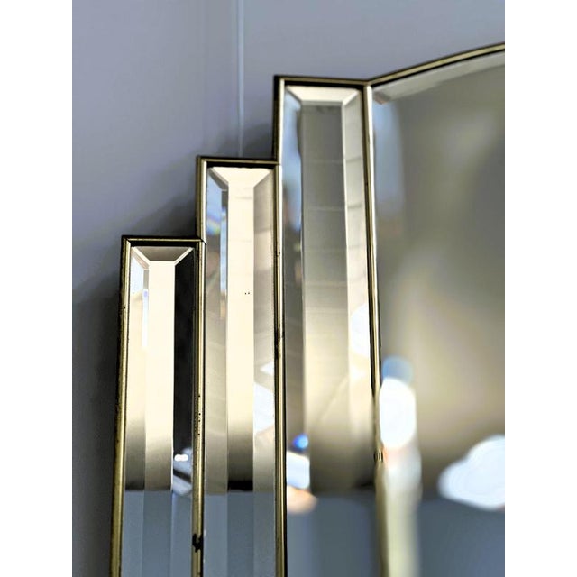 An elegant art deco style wall mirror with a distinctive stepped geometric design, beautifully reflecting the...