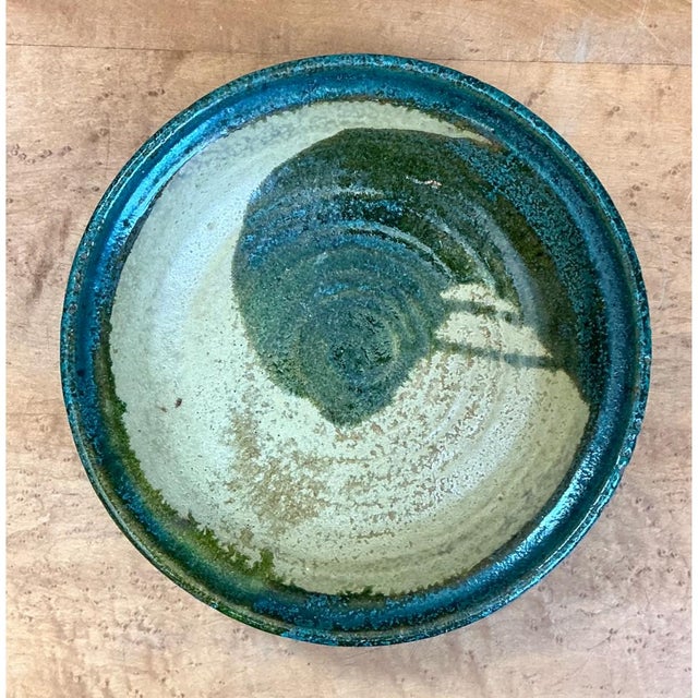 Handcrafted during the mid-20th century, this vintage studio pottery bowl displays a striking abstract composition...