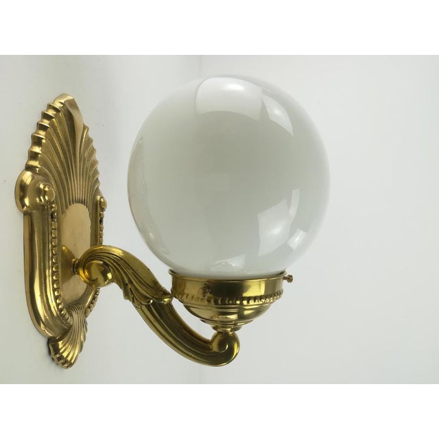 Solid brass wall lamps with two-pointed opal shade. European Plug (up to 250V).The wiring of this item may be original and...