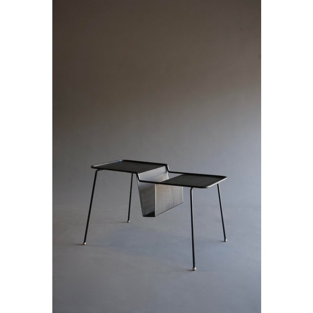 A rare perforated metal magazine table with brass ball feet. Designed by Mathieu Matégot and manufactured for a short...