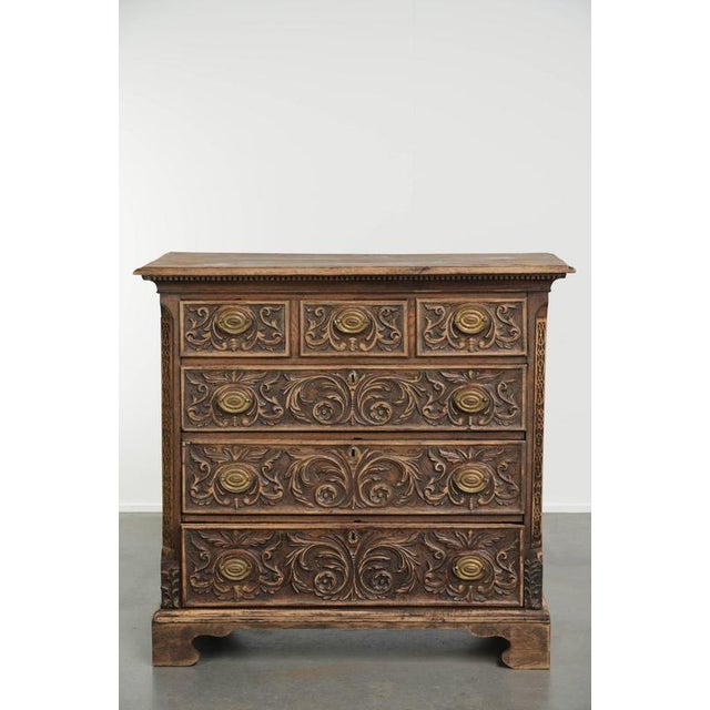 This beautiful, richly carved English oak chest of drawers dates from the 18th century and features unique details and a...