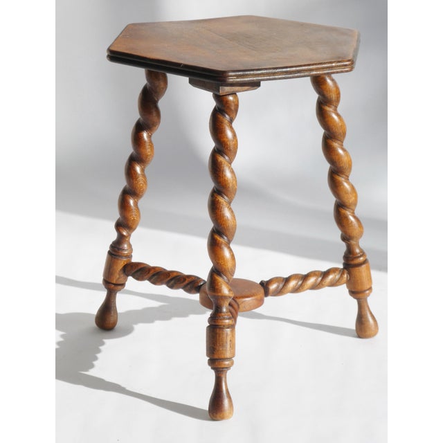 A small antique wooden stool with a hexagon top. The table is standing on three barley twist legs. Overall in good...