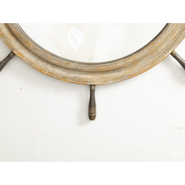 An English ship wheel shaped mirror from the mid 20th century, with nicely distressed patina. Created in England during...
