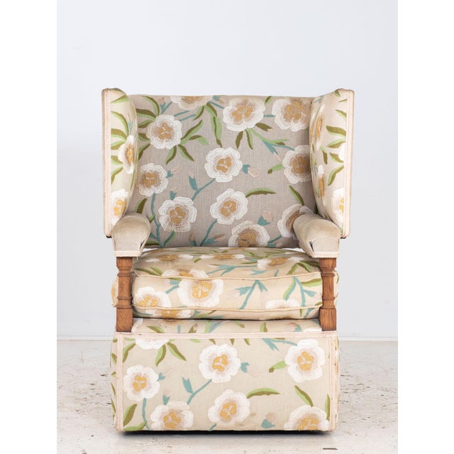 This upholstered Knowle-style armchair features a tailored silhouette with a high back, sloping arms, and comfortable...