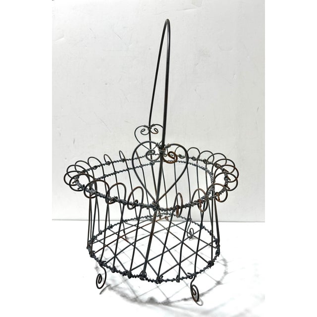 A late 19th-century handmade Victorian wire egg gathering basket with beautifully detailed scrollwork and elevated form....