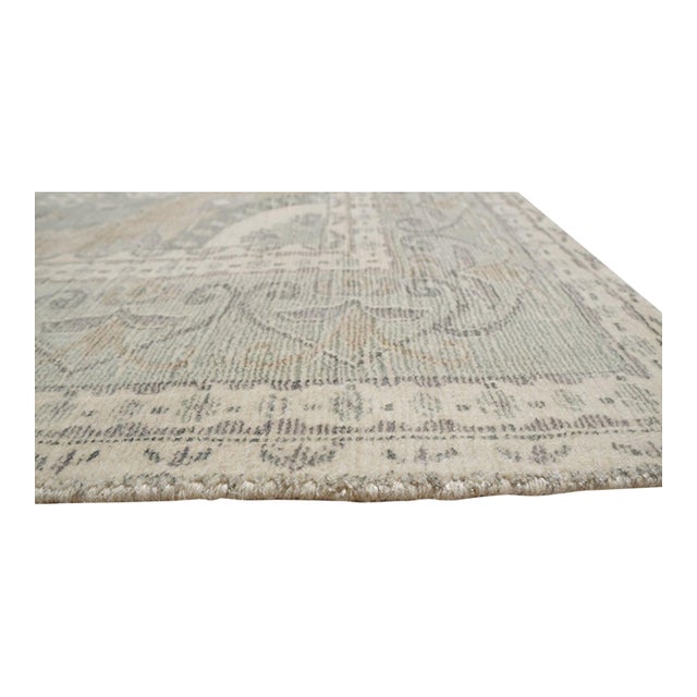 A hand-knotted wool rug, made in India and measuring 4' x 6'. Floral drawing carried across the field inside a traditional...