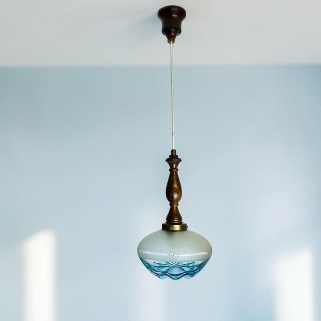 Vintage Mid-Century Modern pendant light featuring a beautifully turned wooden stem in a warm teak finish, accented with...
