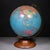 ABOUT A mid-century Replogle 12 inch world globe with brass plated metal bracket and solid wooden base. CREATOR Replogle...