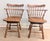 This is a pair of solid maple swivel dining chairs are in the Colonial Windsor style, with a comb back and saddle seat....