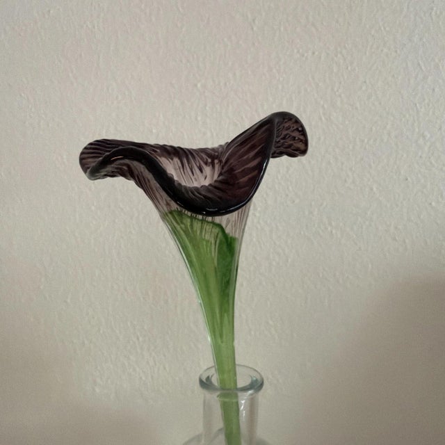 This hand-blown Murano style vase features a beautiful purple flower with a straight stem, adding a touch of elegance to...