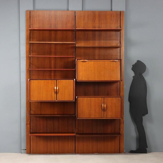 Vintage double-span bookcase with wainscoting and adjustable shelves and storage elements in teak veneer. This piece is...