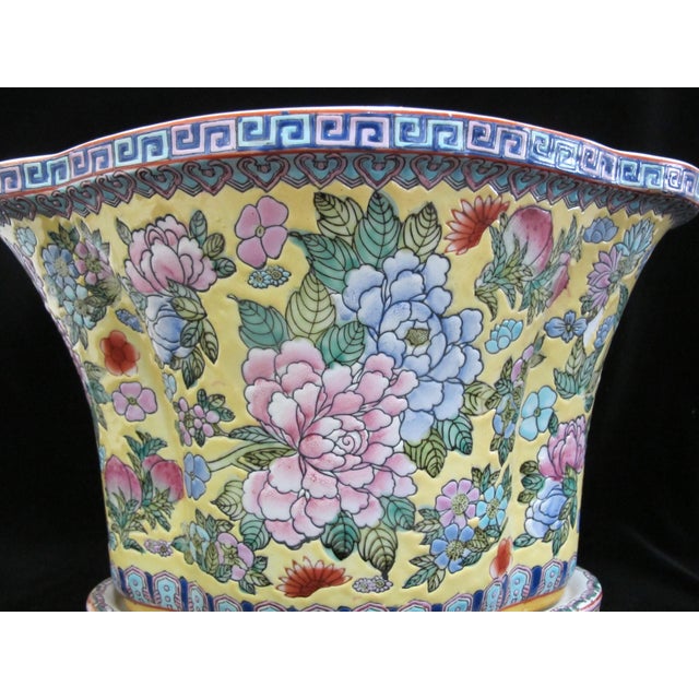 Chinese porcelain cache pot with porcelain stand. Vibrant blue, pink, and red flowers on yellow backdrop. Four rounded...