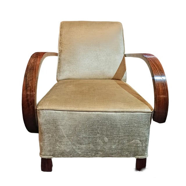 A pair of large, upholstered armchairs in the Art Deco style. The furniture features simple, geometric forms...