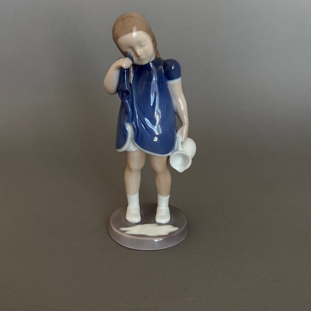 Sweet young girl, wiping her eyes with her dress and crying over spilled milk.