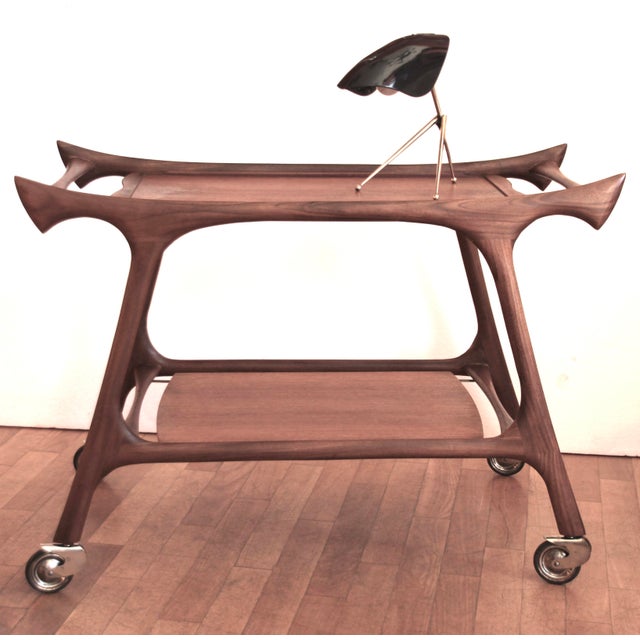 This teak bar cart was likely made in Italy in the 1950s. The tray on the upper level is removable. The elegant, curved...