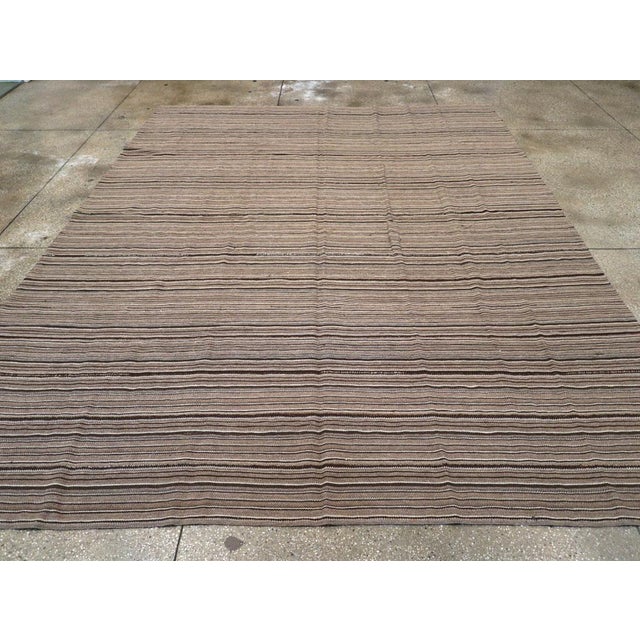This Mid-20th century Turkish Flatweave Kilim rug, features a refined horizontal striped design woven in a palette of...